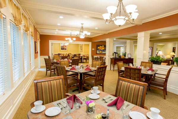 Well-lit dining room with set tables and decorative centerpieces.