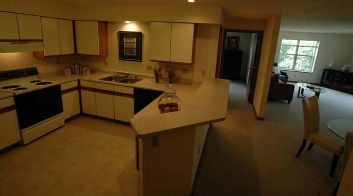 Bright kitchen area with seating and living room visible