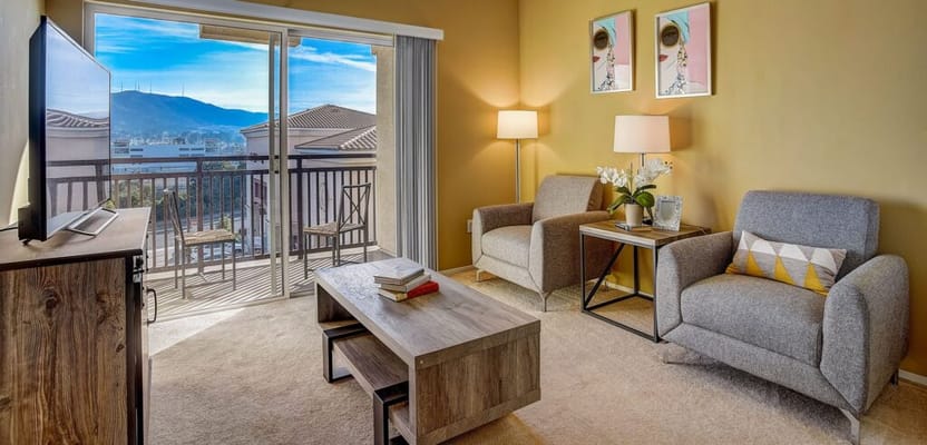 Bright living room with two armchairs, a coffee table, and a balcony view