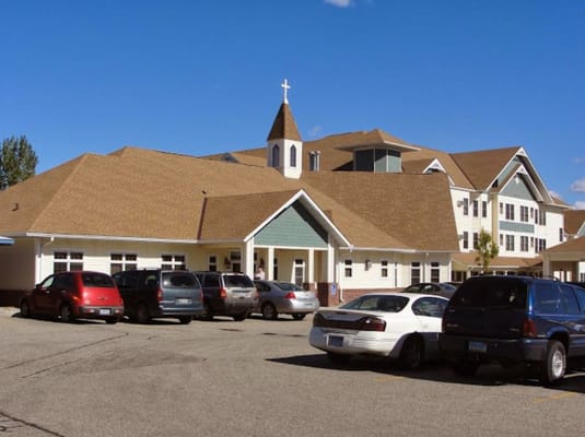 Exterior view of Pioneer House Assisted Living with parked cars