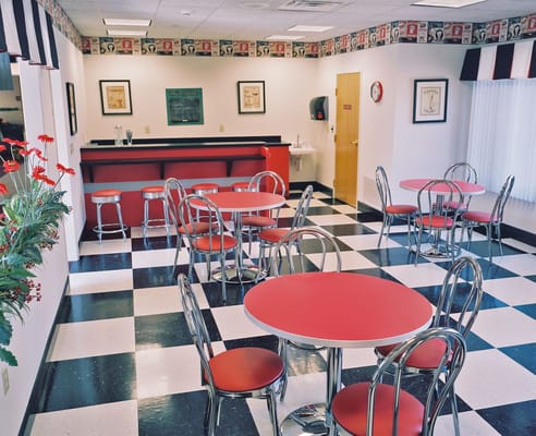 Bright dining area with red tables and checkered floor