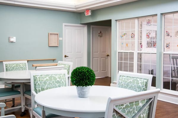 Bright common area with round tables and green decor