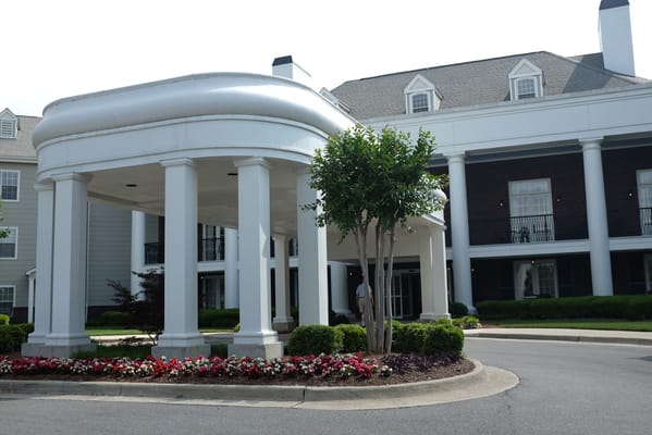 Entrance of a senior living facility with columns and flowers