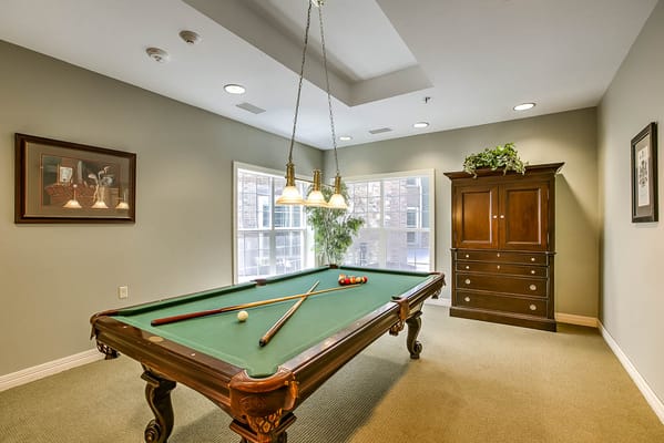 Billiards table with pool cues in a well-lit room