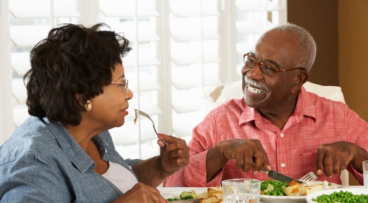 Two seniors enjoying a meal together at a dining table.