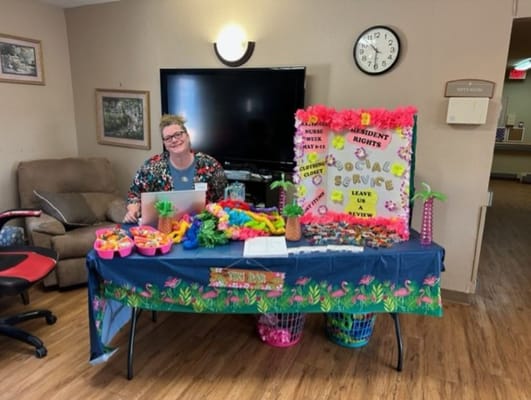 A staff member at a decorated table for a social service event.