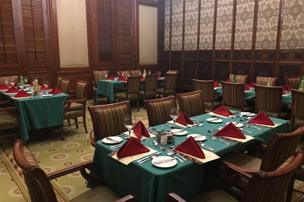 Elegant dining room set with teal tablecloths and red napkins.