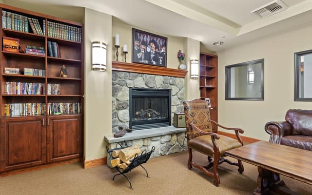 A cozy living room with a stone fireplace, bookshelves, and comfortable seating.