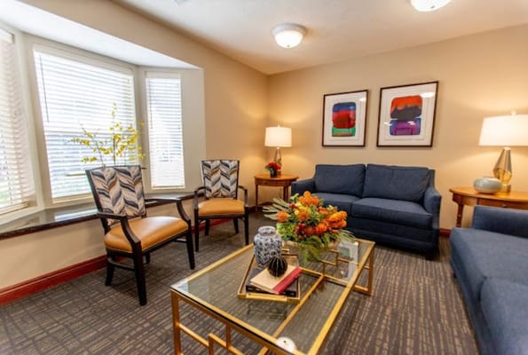Comfortable living room with blue sofas and chairs, decorative plants, and artwork.