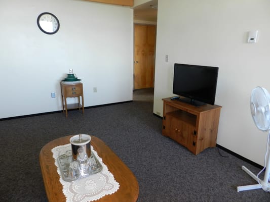 A cozy living room with a wooden table, a TV stand, and a side table