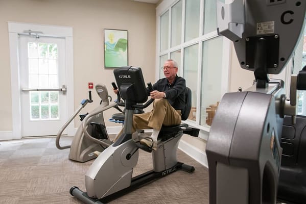 Resident exercising on a recumbent bike in the fitness area