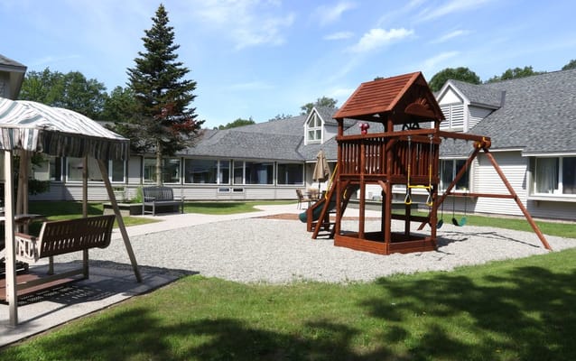 Outdoor playground with swings and a slide at Starr Farm Nursing Center