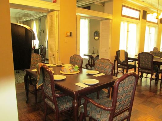 A dining area with wooden tables and patterned chairs, set for a meal.