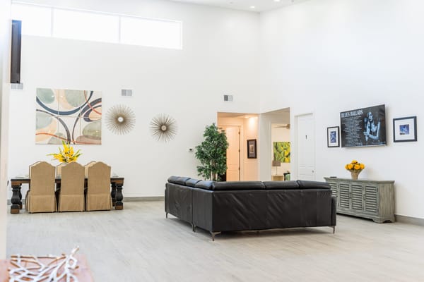 A modern living room with a large sofa, dining area, and decorative wall art.