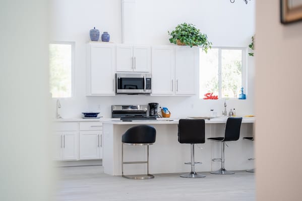 Bright and spacious kitchen area with black bar stools and white cabinetry.