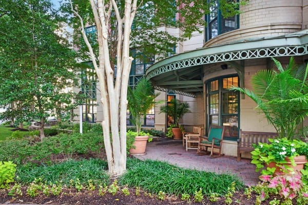 Entrance area with benches, plants, and trees at Sunrise of Connecticut Ave.
