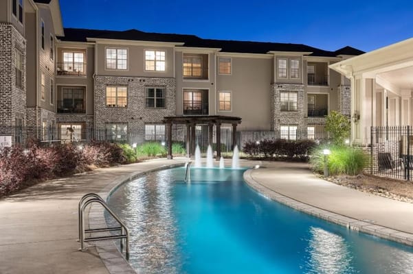 Evening view of the pool area with fountains at The Claiborne at Hattiesburg.