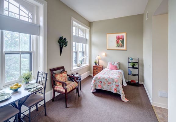 Bright bedroom with floral bedding and a cozy seating area