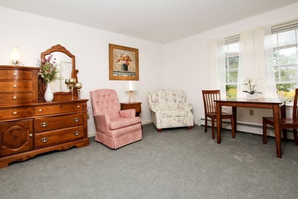 Living room with two armchairs, a wooden dresser, and a small dining table.