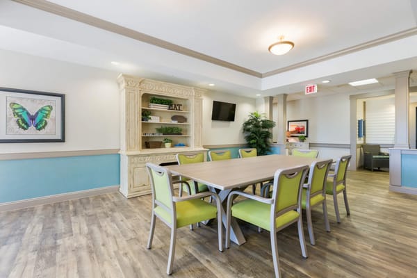 A modern dining room with a large table and colorful chairs.