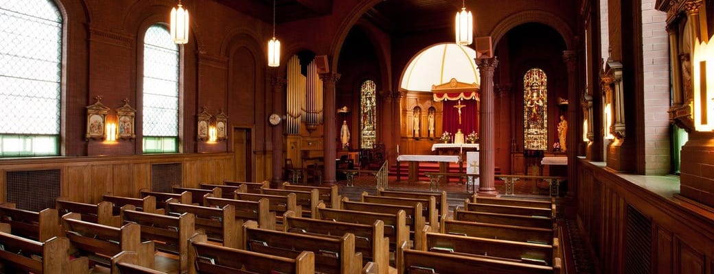 Interior view of the chapel with wooden pews and stained glass windows.