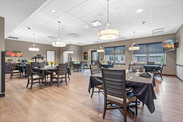 Dining area with tables and chairs, decorated with flowers.