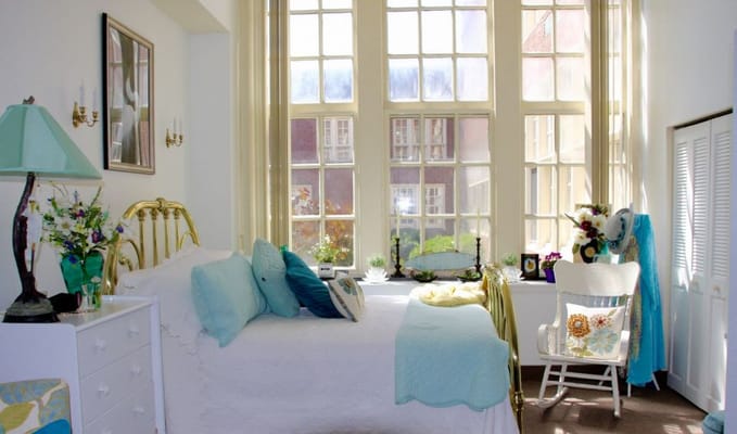 A well-decorated bedroom with a gold bed and large windows.
