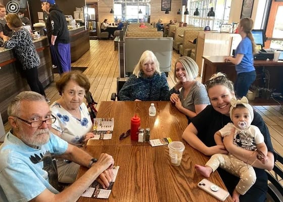 Group of residents and family members at a dining table in a casual setting.