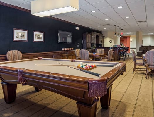 A well-furnished pool room with a billiards table and seating areas