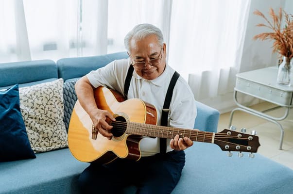 Senior man playing guitar in a bright lounge area
