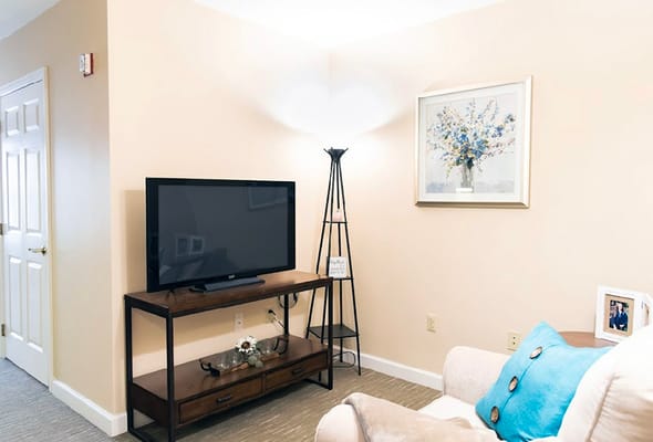 A cozy living room with a TV, decorative lamp, and artwork.