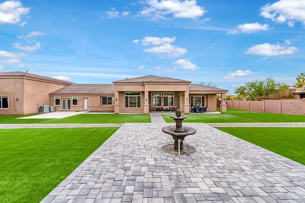 Backyard view of The Valencia Home with landscaped grass and a fountain.