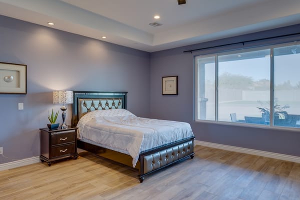 Well-furnished bedroom with a large window and complementary furniture.