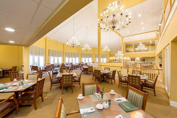 Dining area with tables and chandeliers in a senior living facility