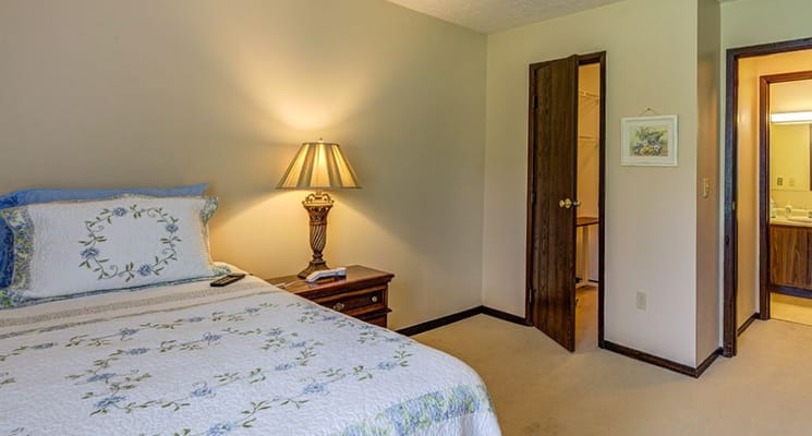 Brightly lit private resident room with a bed and lamp