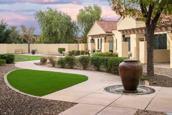 Pathway and garden area with a fountain and greenery at The Village of Ocotillo.