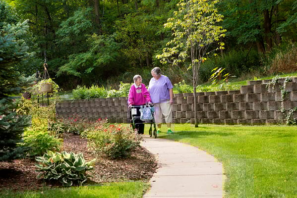 Two residents walking together on a garden path.