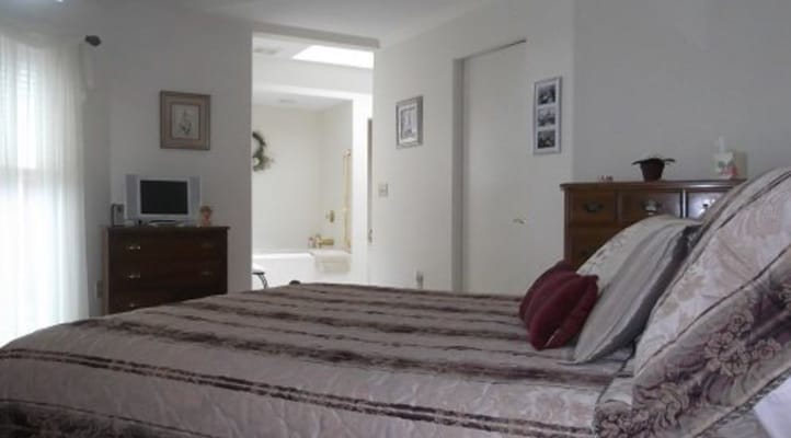 A cozy bedroom with a bed, dresser, and television
