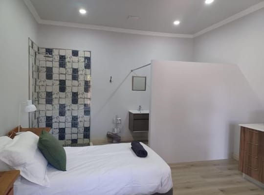 A cozy bedroom featuring a bed, decorative pillow, and bathroom area.