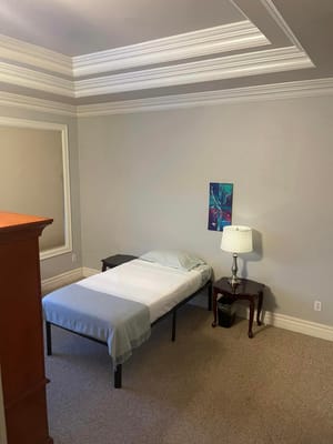 Simple bedroom with a bed, lamp, and artwork on the wall