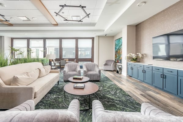 A comfortable common area with seating, plants, and art at Thrive at Montvale.