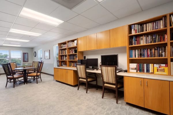 Bright library space with computers, bookshelves, and a dining table