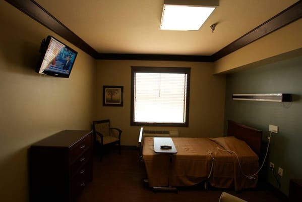 Interior view of a private resident room with a bed and TV