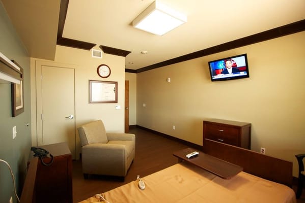 A resident room with a bed, chair, and TV