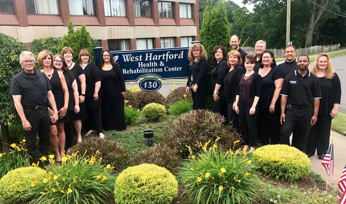 Staff posing together in front of the facility sign