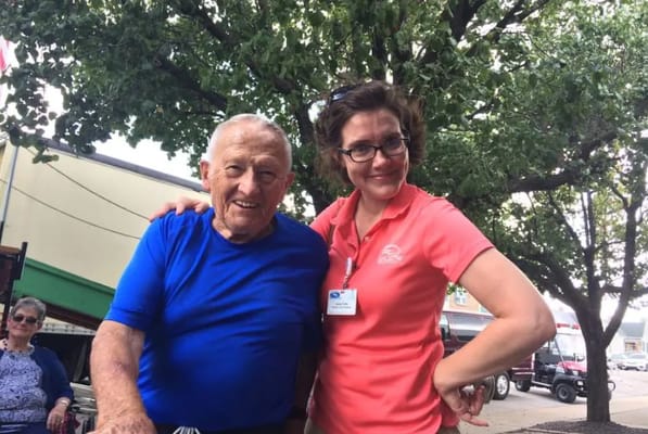 An elderly man and staff member posing outdoors together