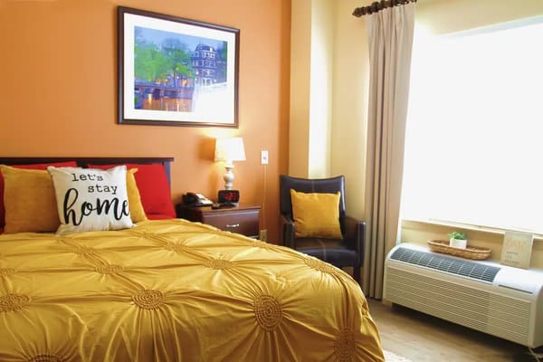 A well-decorated bedroom with a yellow bedspread and artwork.