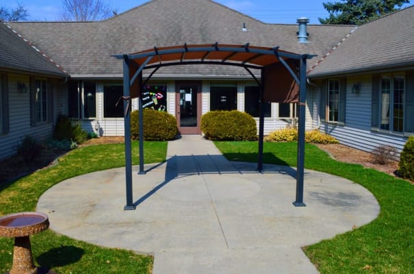 View of the entrance with a shaded canopy and landscaped pathway