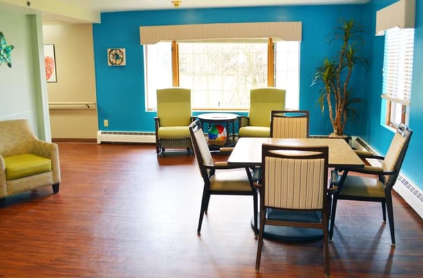 Spacious common area with seating and large windows at Wyndemere Memory Care.