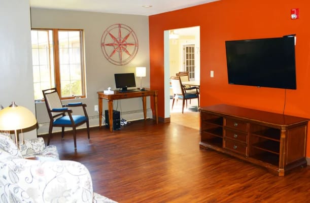 Bright common area with a desk and TV in Wyndemere Memory Care.